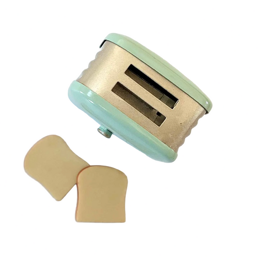 Miniature dollhouse toaster with bread slices on a white background