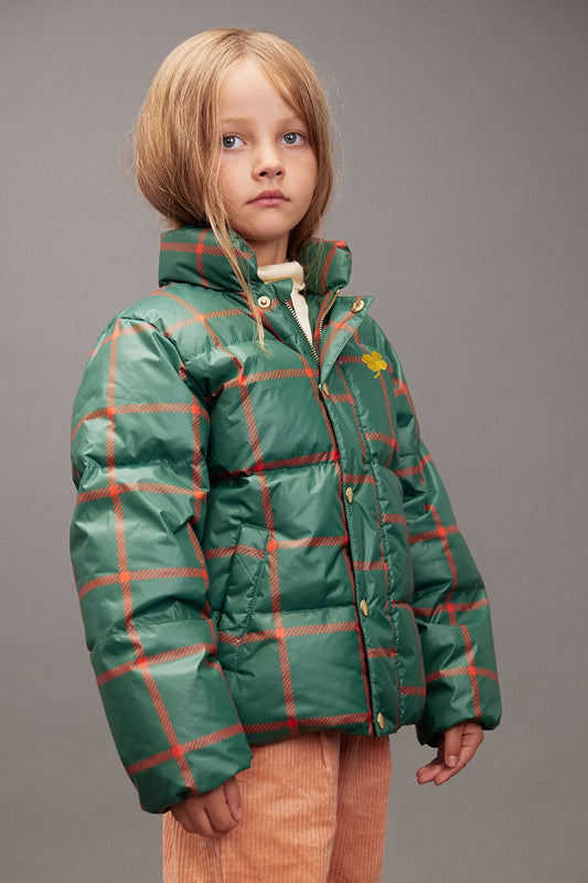 Child wearing a green plaid jacket on a gray background