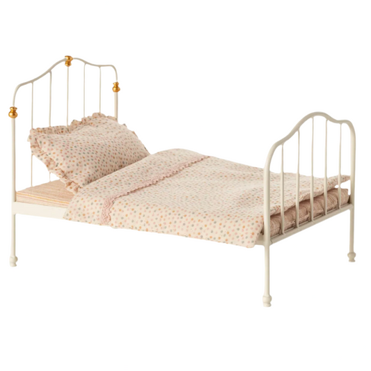 Small bed with gold frame and beige bedding on a white background