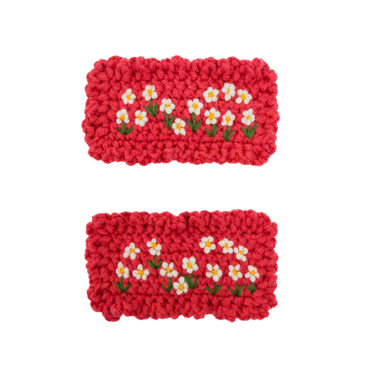Two red crocheted coasters with floral patterns on a white background