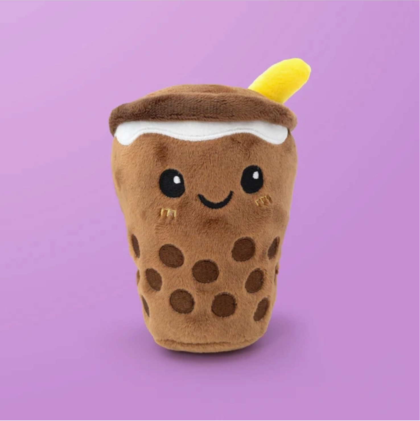 Plush toy resembling a brown polka dot drink with a yellow straw on a purple background