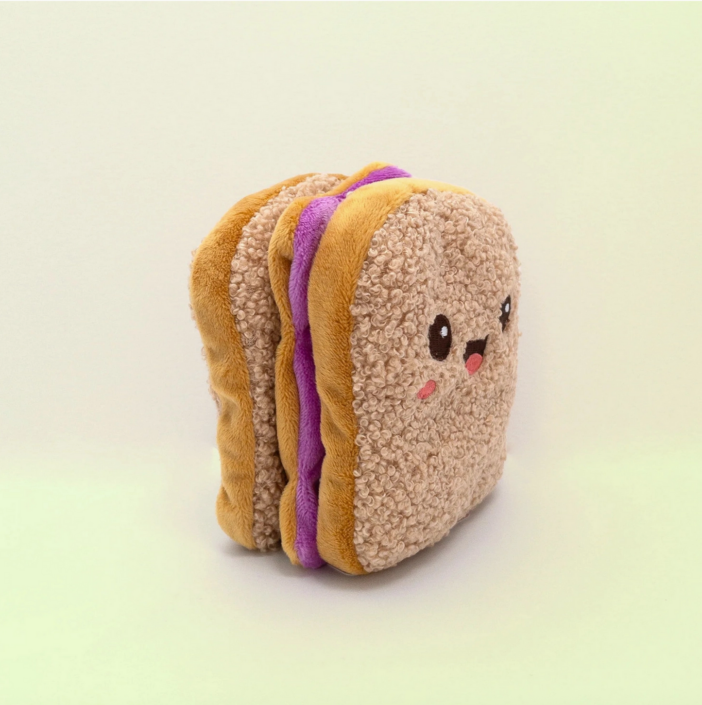 Plush toy resembling a sandwich with a face on a light background