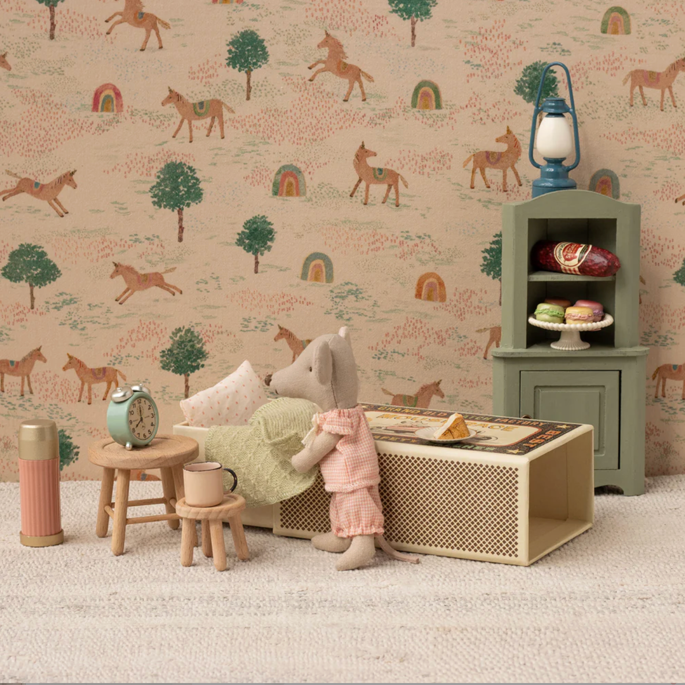 Children's room with toy mouse, furniture, and decorative items against a wallpaper with animal patterns.